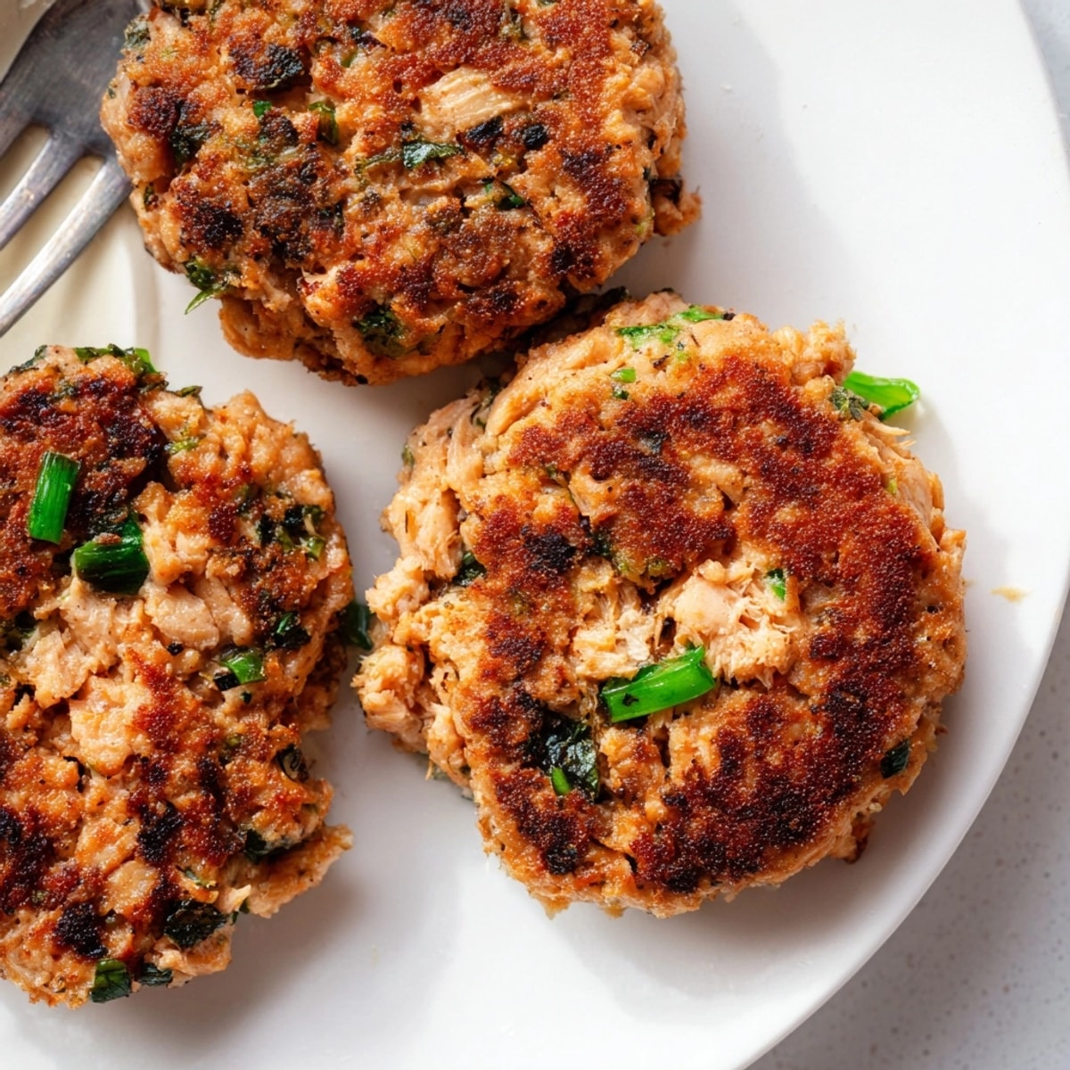 Golden brown Garlic Ginger Salmon Patties sizzling in a pan, ready to serve.