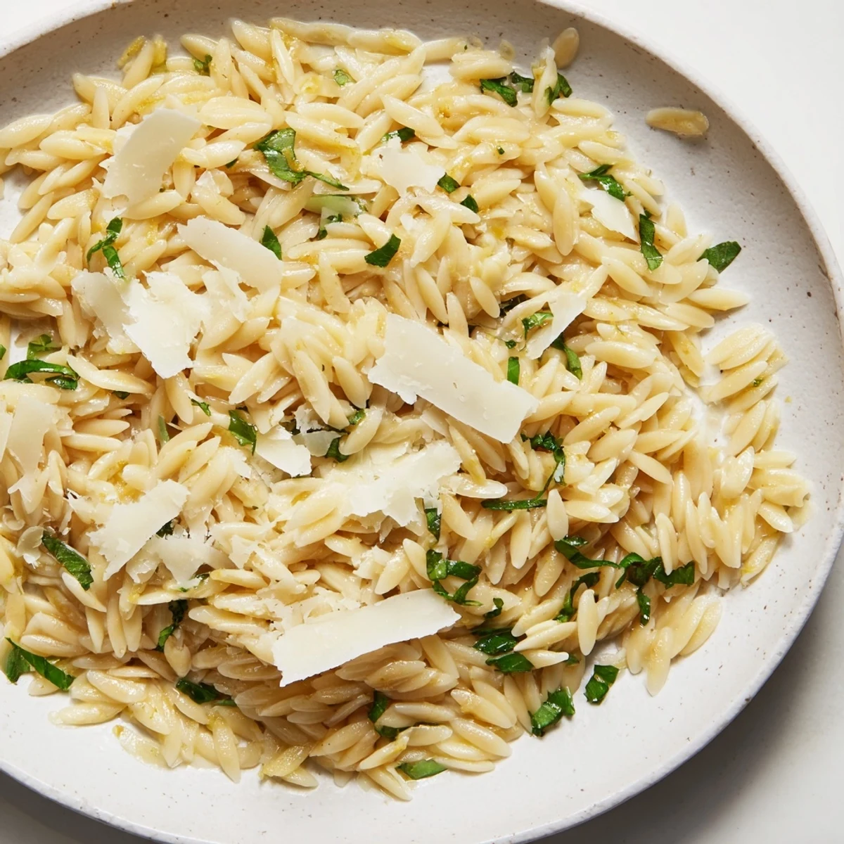 A delicious orzo with lemon, herbs, and parmesan garnished with fresh parsley.