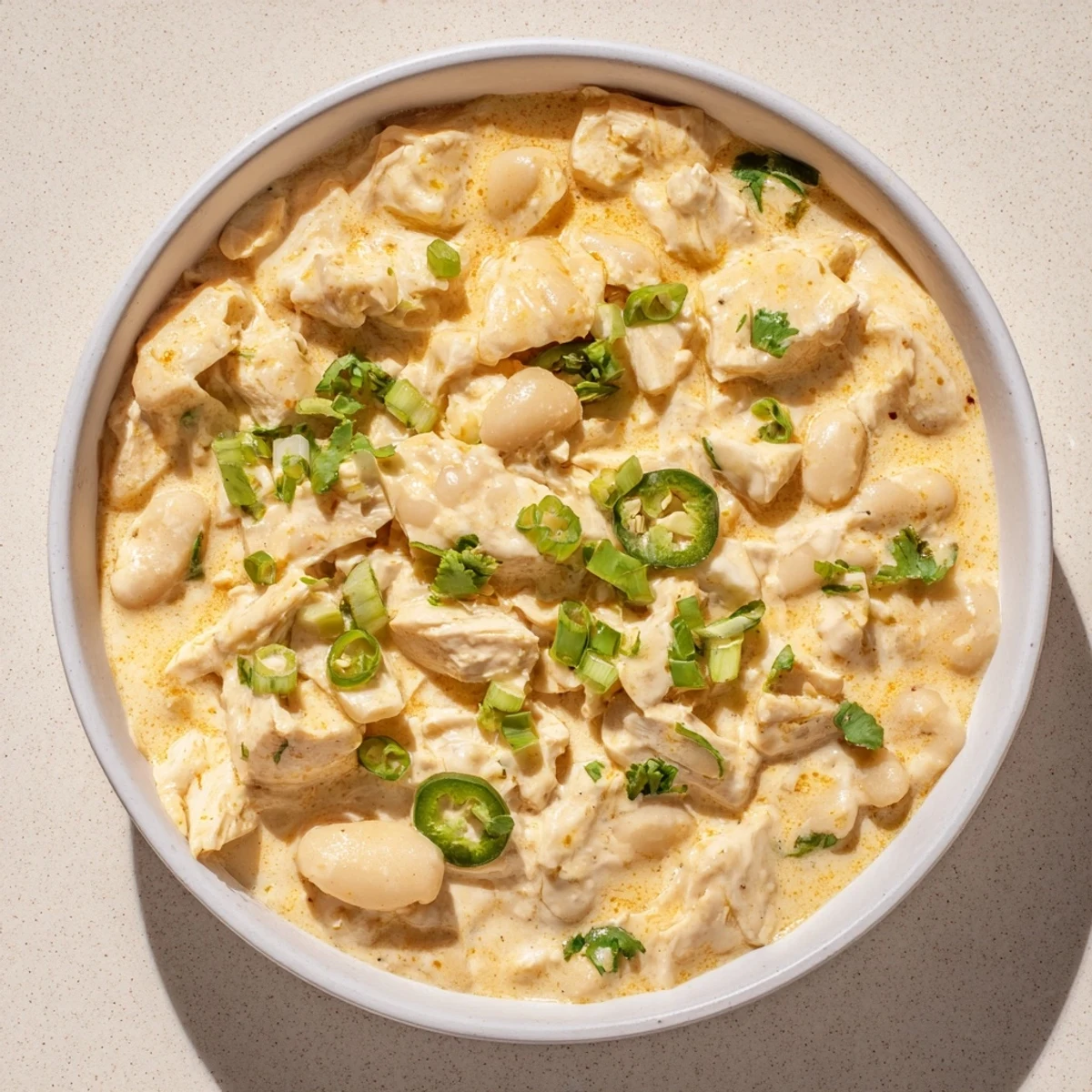 Spoonful of creamy white chicken chili with beans, a hearty and warming dish perfect for any evening.