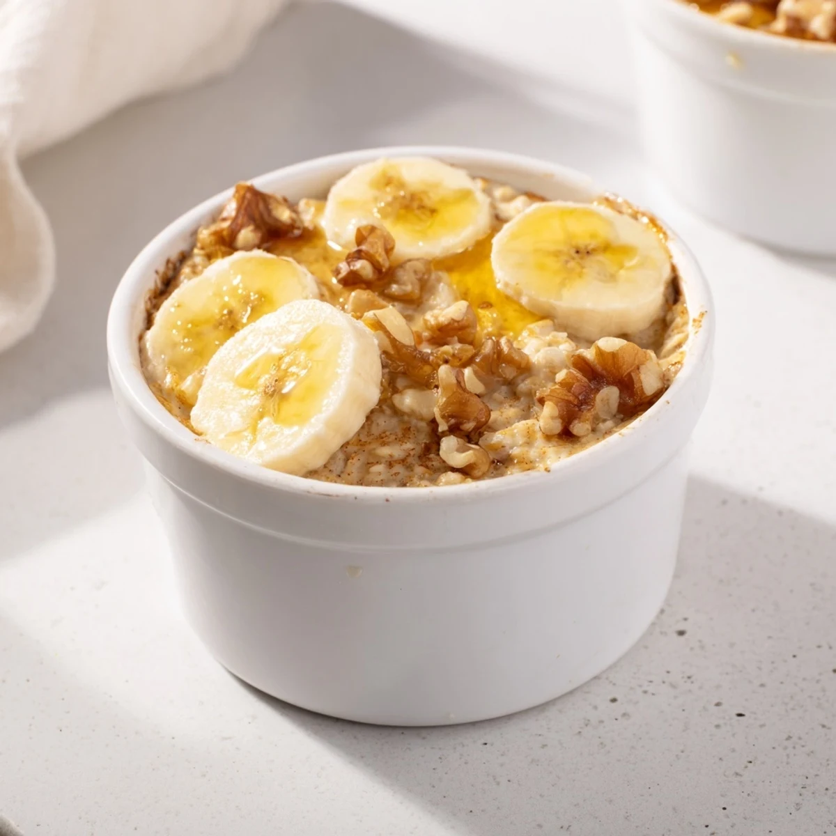 Warm, bubbling baked oats with ripe banana baked inside individual ramekins, a comforting morning meal.