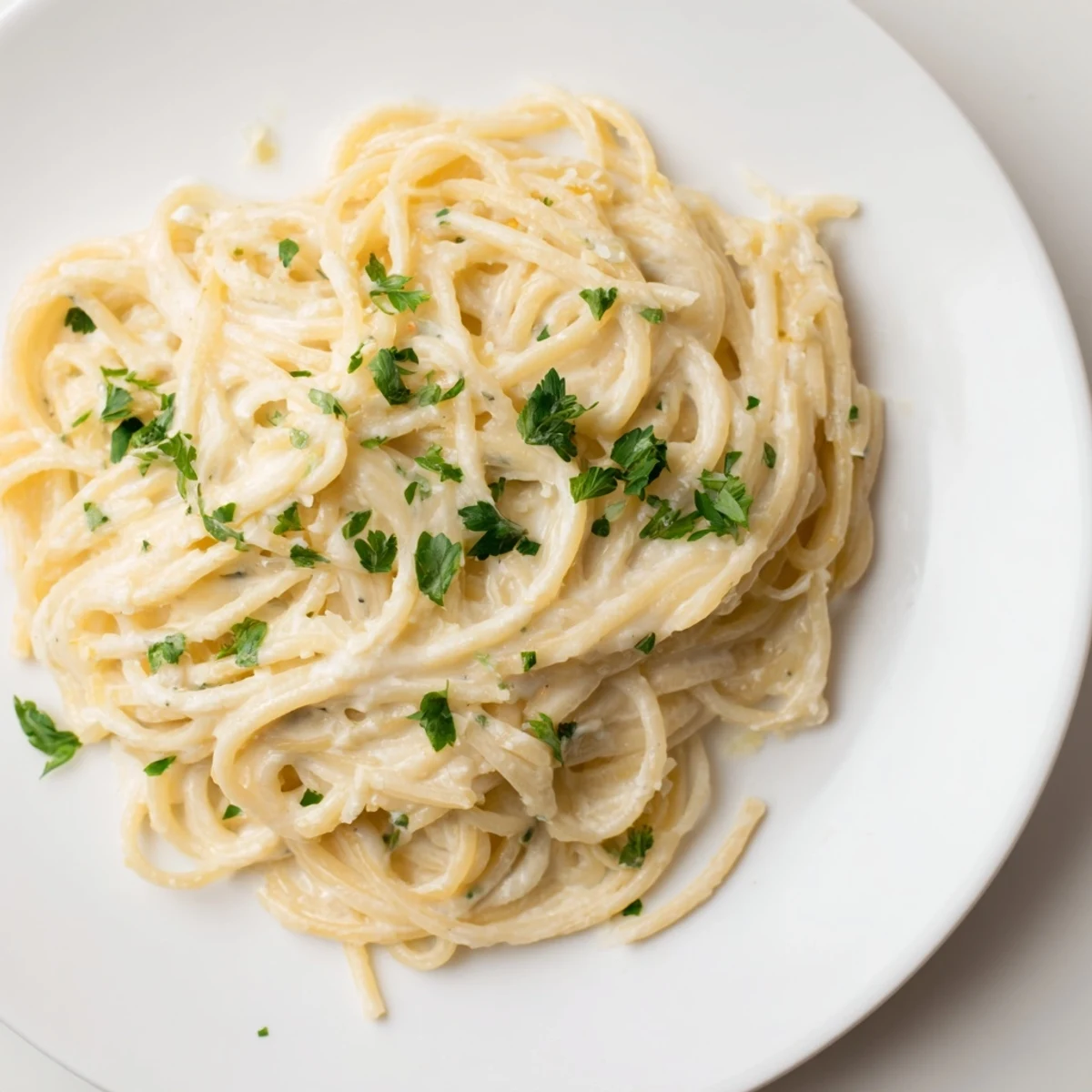 Golden, creamy Three-Cheese Spaghetti, perfectly coated and ready to serve with fresh parsley.