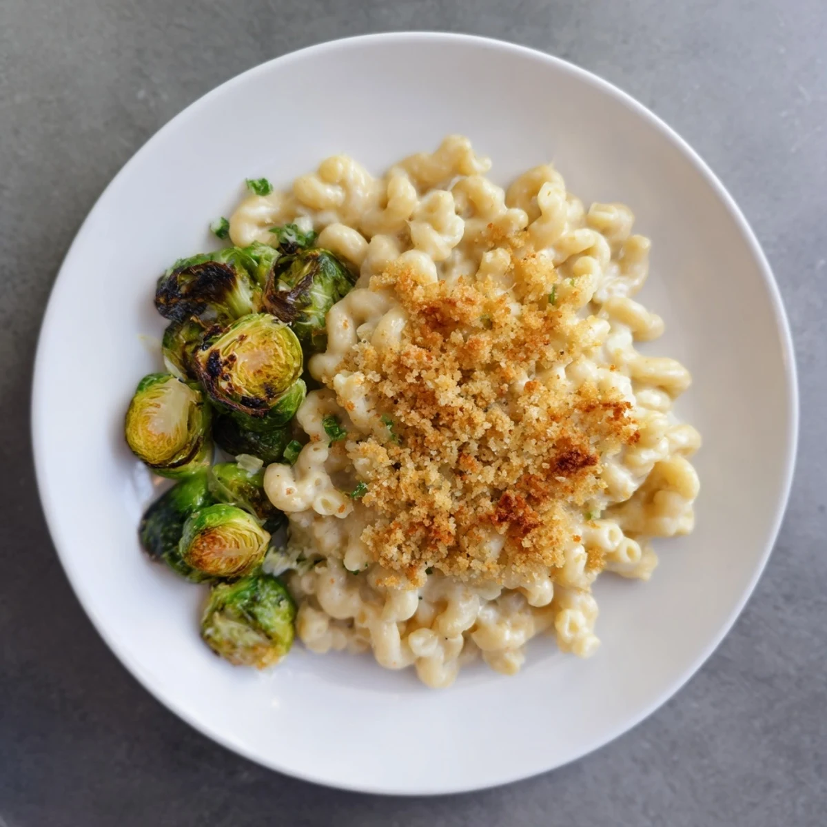 A delicious close-up reveals creamy Sheet Pan Mac and Cheese, studded with roasted Brussels sprouts.