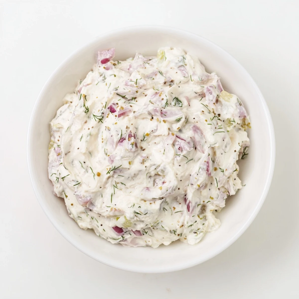 A close-up view of the sweet and sour pickle relish dip with flecks of fresh dill and red onion.