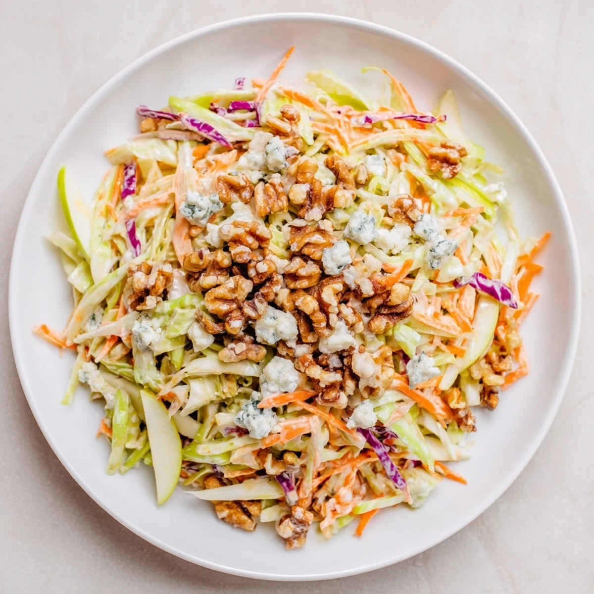 This refreshing Crunchy Apple & Walnut Slaw reveals toasted walnuts and crumbled blue cheese in a lovely bowl.