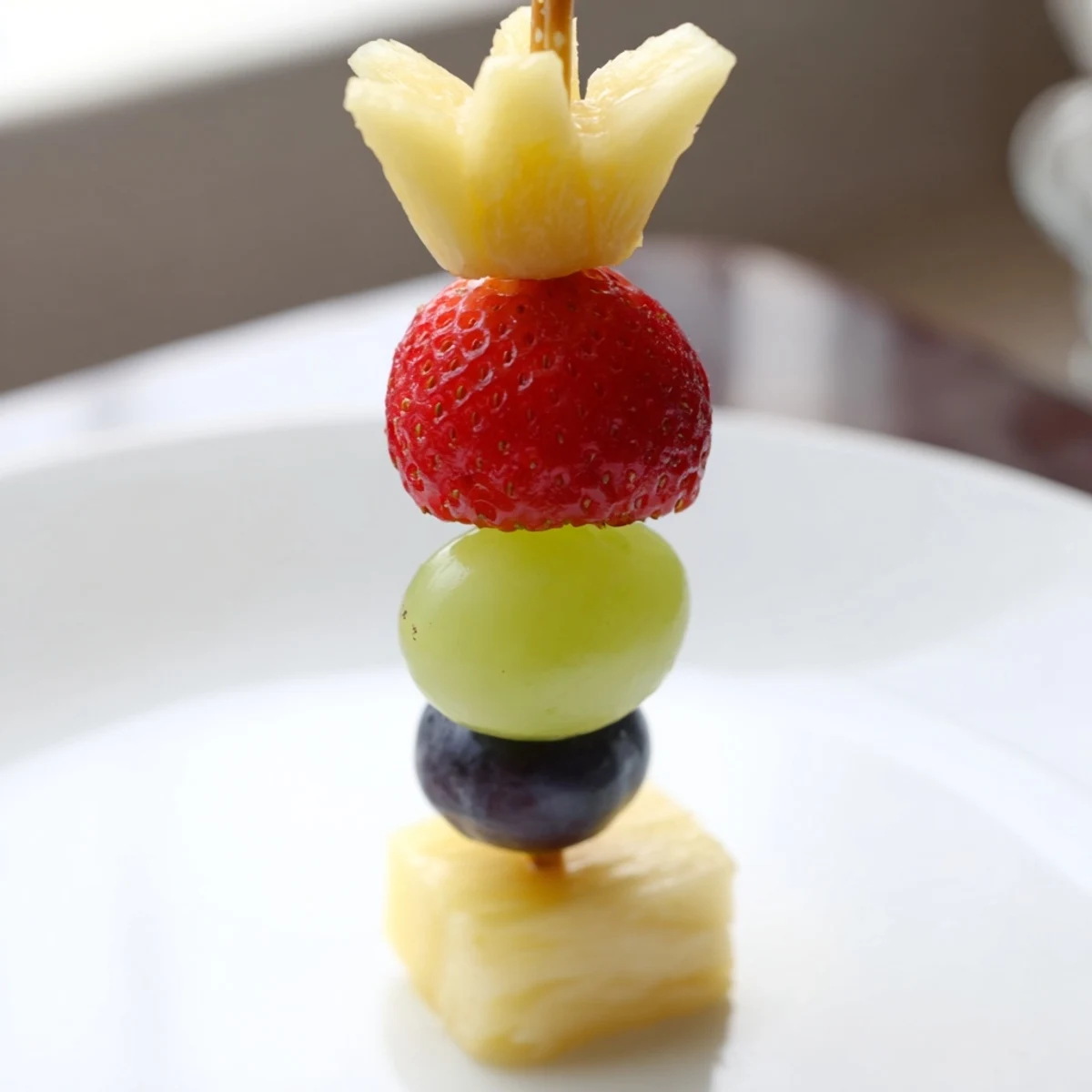 Holiday-ready Christmas Light Fruit Skewers: bright red strawberries, juicy grapes, and pineapple.