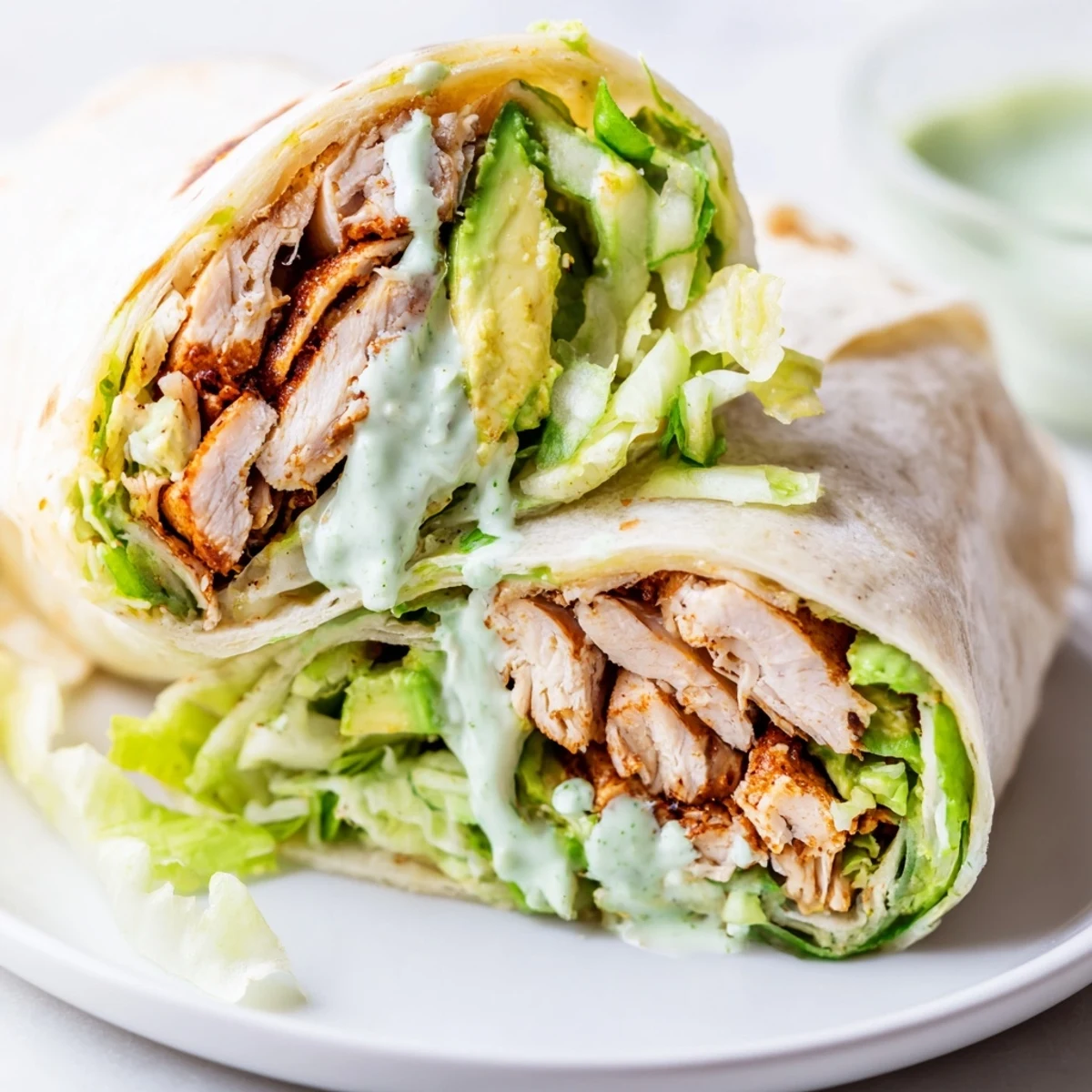 A close-up of the Smoky Chipotle Chicken Wrap sliced in half to reveal layers of juicy chicken, fresh veggies, and sauce.  