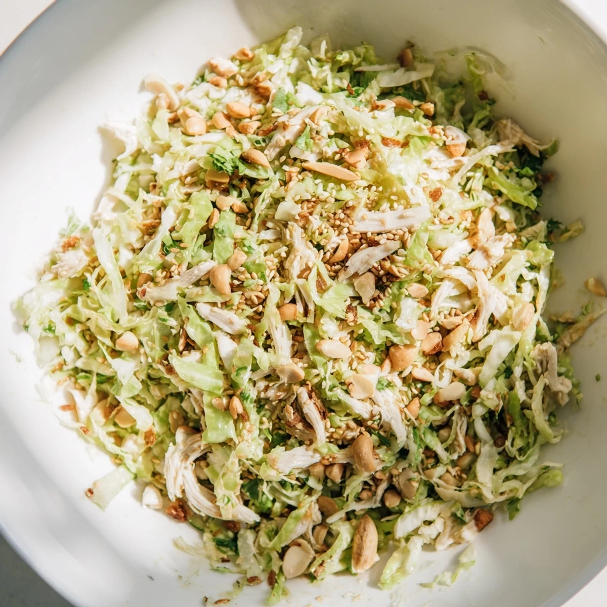 A close-up of crunchy ramen chicken salad with shredded cabbage, carrots, and crisp noodles tossed in sesame dressing.