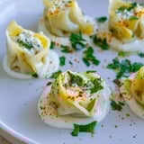 Close-up of golden, cooked Turkish cheesy manti, overflowing with a creamy cheese filling.