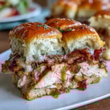 Warm Derby Day Hot Brown sliders with turkey, bacon, and creamy Mornay sauce on soft rolls, topped with melted cheese and fresh parsley.