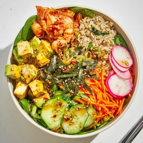 A vibrant fermented vegetable bowl filled with kimchi, fresh greens, and grains.  