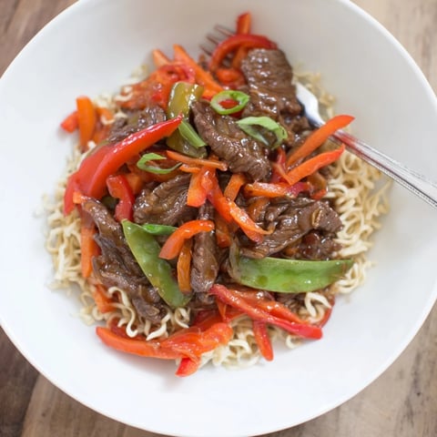 Steaming Teriyaki Beef & Noodle Bowl with glistening sauce, topped with sesame seeds.