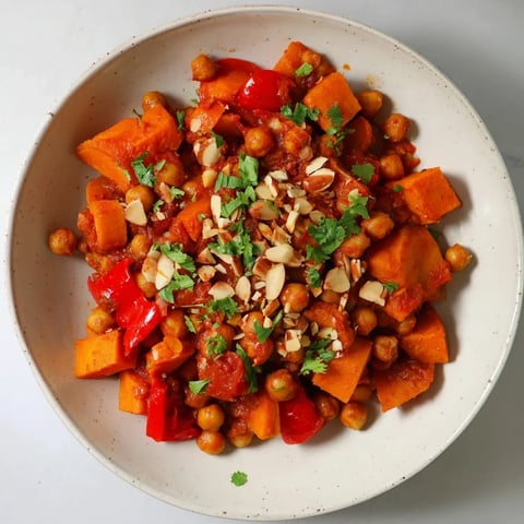 Steaming Moroccan Chickpea & Sweet Potato Tagine, richly spiced and garnished with fresh cilantro, ready to serve.