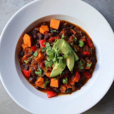 Steaming bowl of Sweet Potato & Black Bean Chili, garnished with cilantro, ready to eat.