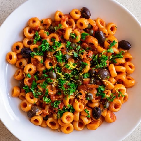 A steaming bowl of Puttanesca Ditalini, a flavorful Italian pasta dish with olives and capers.