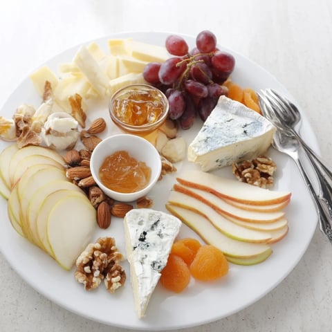Beautiful cheese platter artfully arranged with French cheeses and fruit, perfect for sharing.