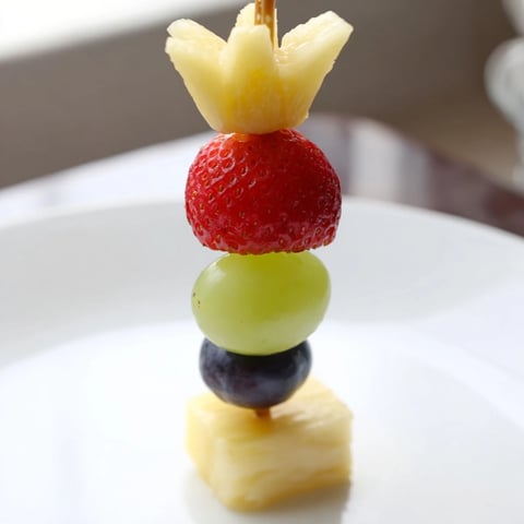 Holiday-ready Christmas Light Fruit Skewers: bright red strawberries, juicy grapes, and pineapple.