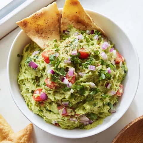 Golden-brown pita chips and vibrant guacamole in a tempting bowl, the perfect party recipe.
