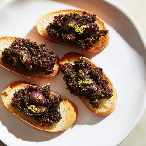 Black Olive Tapenade served with golden brown crostini, a savory appetizer perfect for sharing.