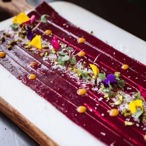 A dramatic photo of "The Modernist Stripe" appetizer with layered purées and vibrant garnishes.