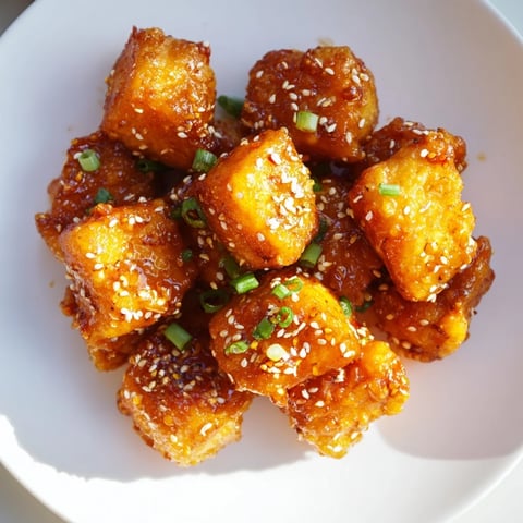 Golden-brown Honey-Sriracha chicken bites, glistening with a spicy-sweet sauce, ready to serve.
