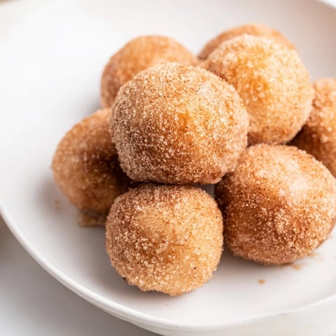 Golden brown air fryer cinnamon donuts, freshly coated with sweet cinnamon sugar, ready to eat.