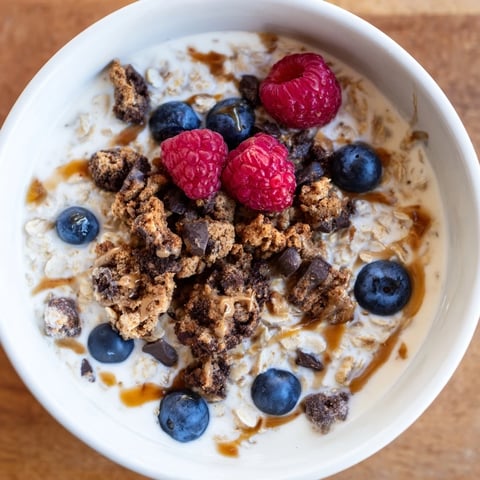 Creamy Overnight Oats Gourmet Makeover topped with berries, nut butter swirl, and cookie crumbs.