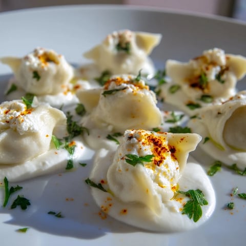 Steaming Turkish cheesy manti dumplings topped with garlicky yogurt and vibrant spiced butter.