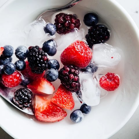 A refreshing Nature's Cereal Bowl, berries glistening in chilled coconut water, a perfect vegan breakfast.