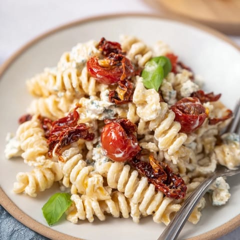 Golden feta topping a hearty pasta with vibrant cherry tomatoes and fresh basil.  