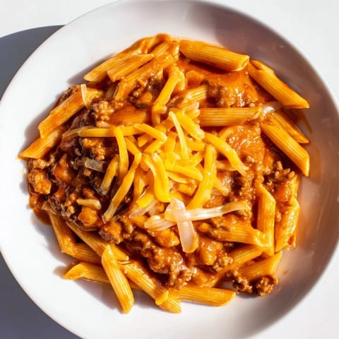 A steaming bowl of Easy Beef Enchilada Pasta, topped with melted cheddar cheese ready to serve.