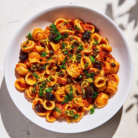 Close-up of al dente Puttanesca Ditalini pasta coated in a rich tomato sauce, ready to serve.