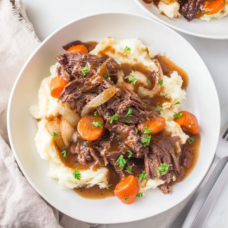 Delicious slow cooker pot roast served over fluffy mashed potatoes, ideal for family meals.