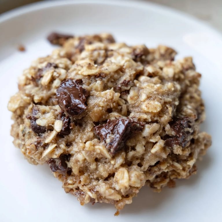 Golden-brown chocolate oatmeal breakfast cookie, loaded with chocolate chips, sits ready to be eaten.