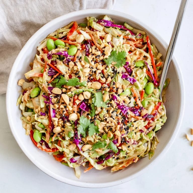 A close-up of the vibrant Crunchy Thai Peanut Salad with red bell pepper strips and fresh cilantro, ready to serve as a refreshing side.  