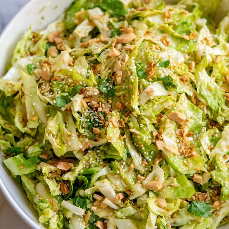 A generous serving of Crunchy Ramen Chicken Salad features fresh cilantro, scallions, and sesame seeds on a white plate.