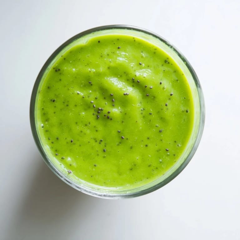 Chilled Green Detox Smoothie in a frosty glass garnished with mint, with lemon wedges and apple slices nearby.