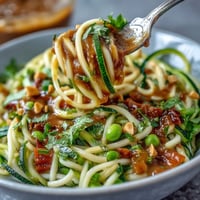 Vibrant zucchini noodles stir-fried with crisp vegetables and drizzled in creamy peanut sauce. Healthy, colorful, and perfect for a quick vegetarian meal.