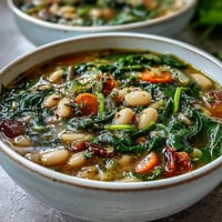 Creamy Tuscan white bean and spinach soup with tender vegetables, aromatic herbs, and a hint of olive oil, perfect for a light summer meal.