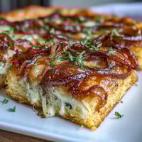 Golden French Onion Puff Pastry Tart with caramelized onions, Gruyère cheese, and thyme on flaky puff pastry, perfect for a savory appetizer or light meal.